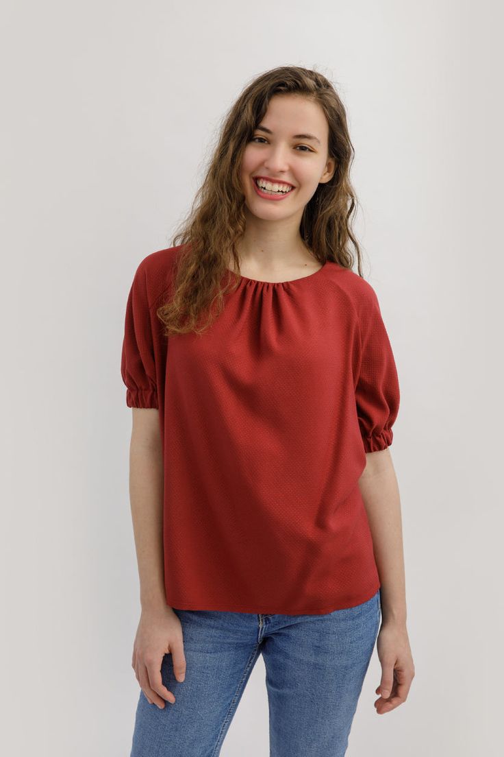 a smiling woman in jeans and a red top