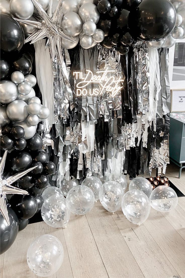 black and silver balloons are hanging from the ceiling