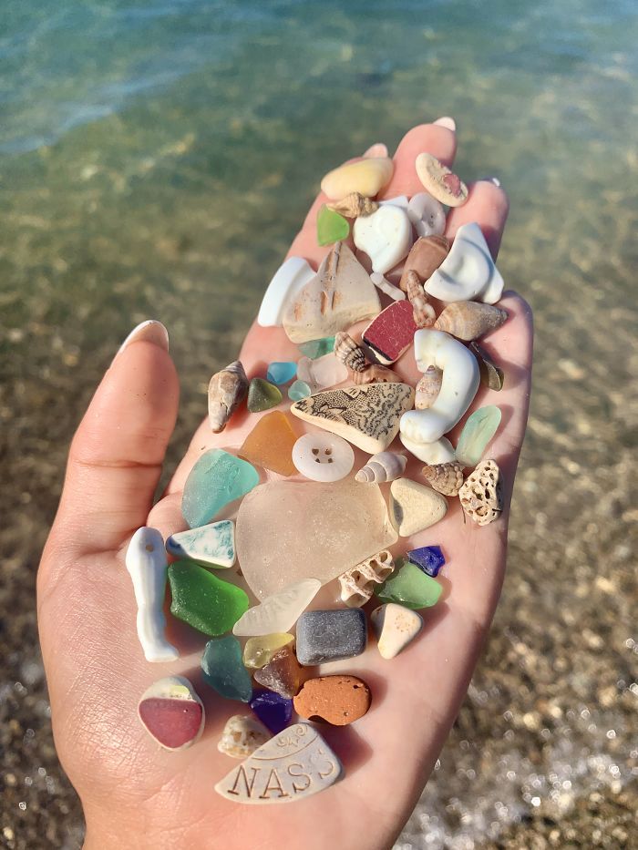 a hand is holding some sea glass on the beach