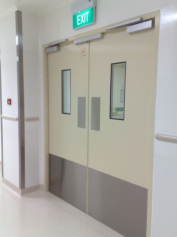 an empty hospital hallway with two doors and signs on the wall above them that read exit