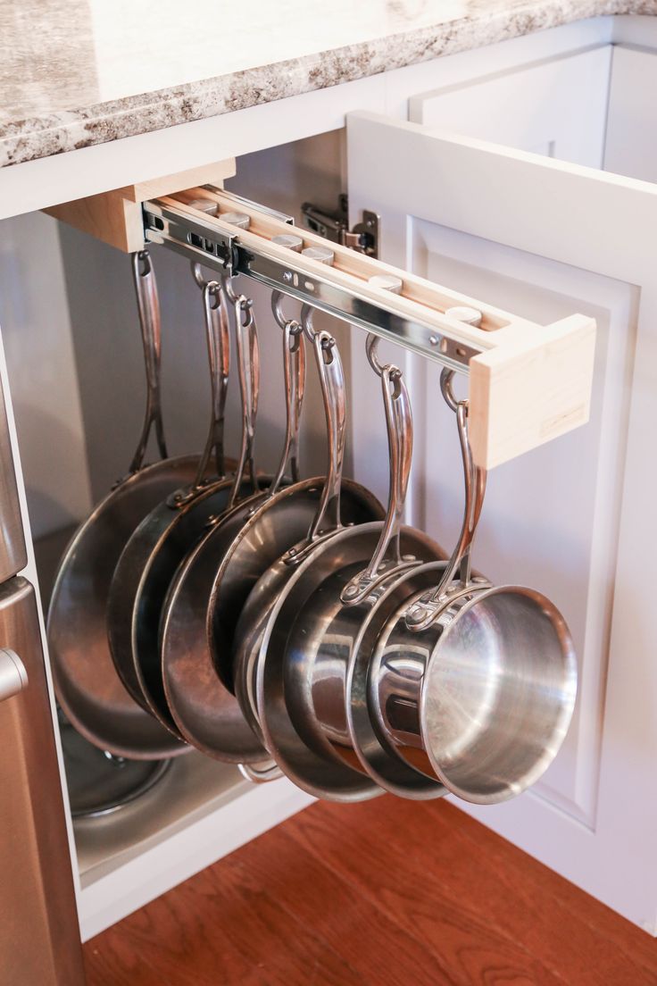 pots and pans are hanging from the pull out rack