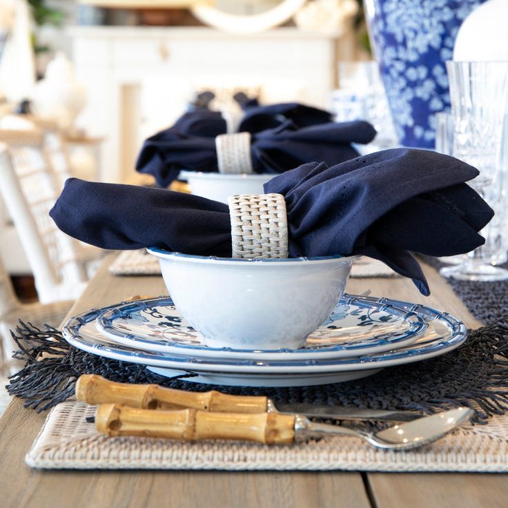 the table is set with blue and white plates, silverware, and napkins