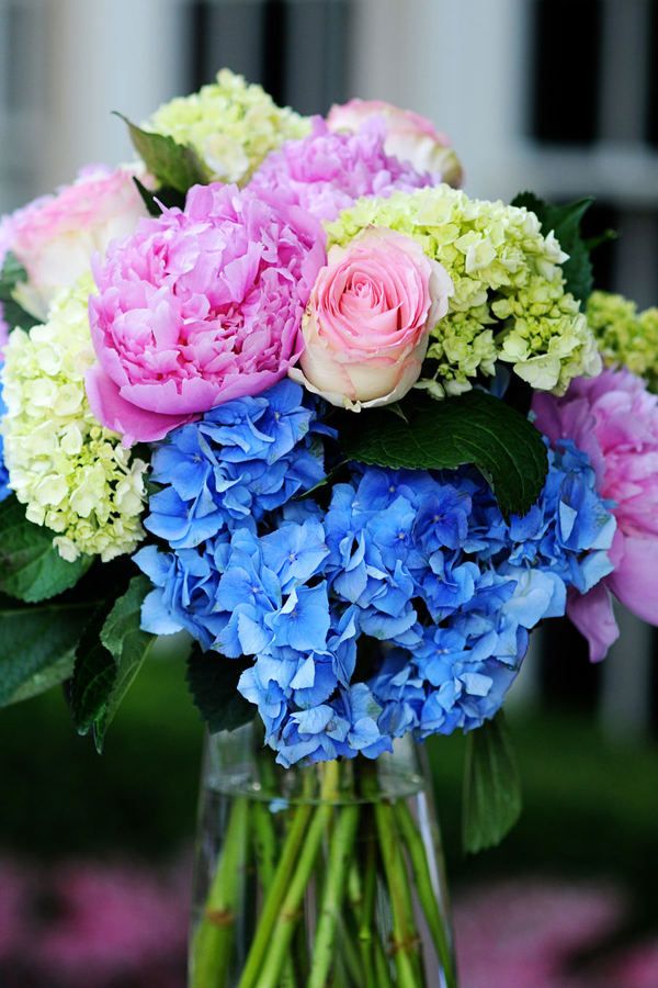 a vase filled with pink, blue and white flowers sitting on top of a table