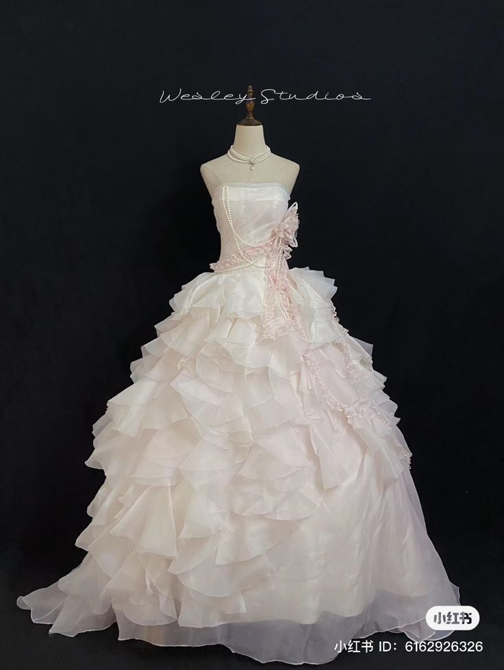 a white wedding dress with ruffles on the skirt is displayed in front of a black background