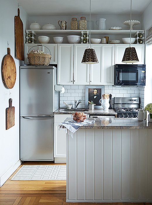 a kitchen with white cabinets and stainless steel appliances, including an island in the middle