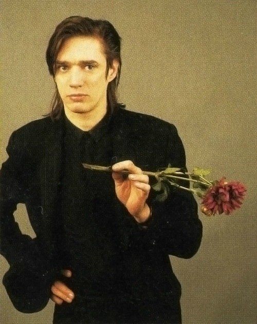 a man holding a flower and looking at the camera