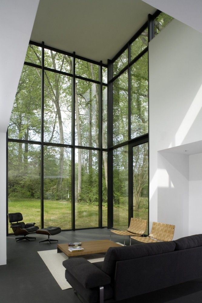 an empty living room with large windows and black furniture in front of the glass wall