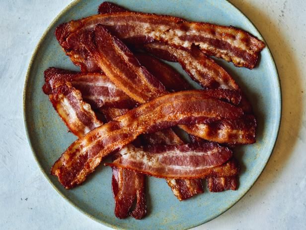 bacon strips on a blue plate sitting on a white counter top, ready to be cooked