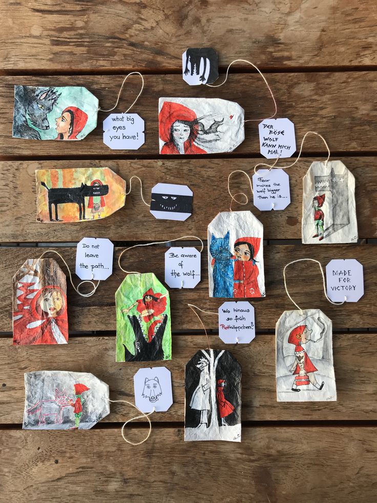 paper tags with pictures of people and animals hanging from strings on a wooden table top