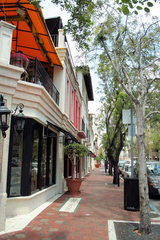 an empty street with cars parked on both sides and trees lining the sidewalk in front