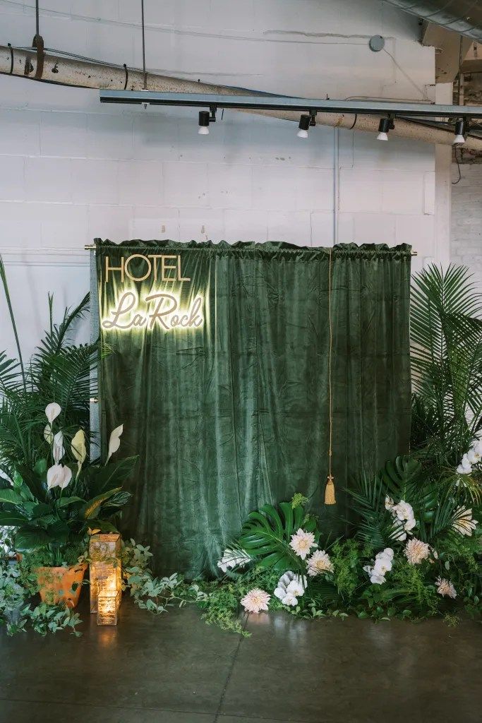 a green backdrop with white flowers and greenery in front of an open air space