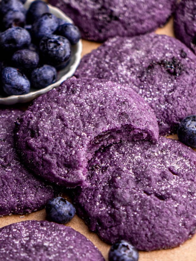 blueberry cookies with powdered sugar on top and bowl of blueberries in the background