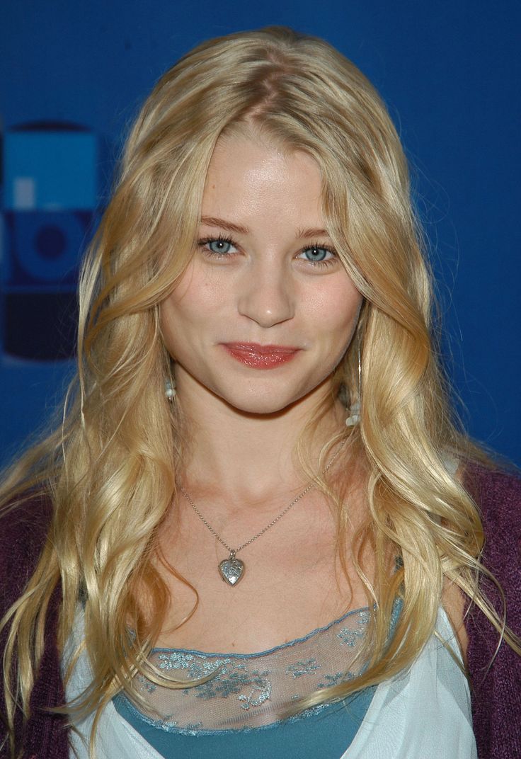 a woman with long blonde hair and blue eyes posing for the camera at an event