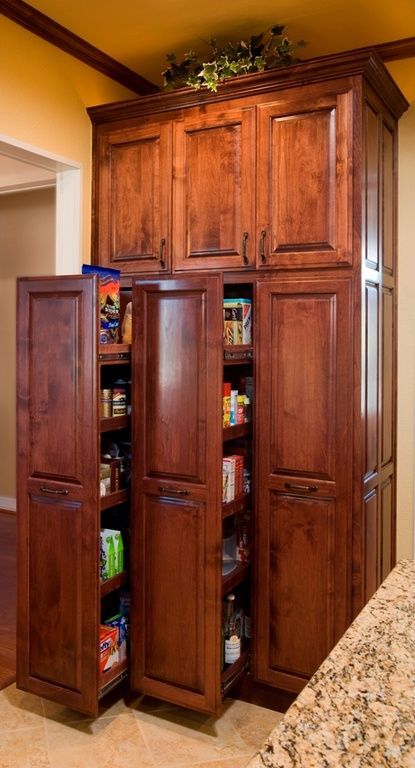 an open pantry in the middle of a kitchen with granite counter tops and wooden cabinets