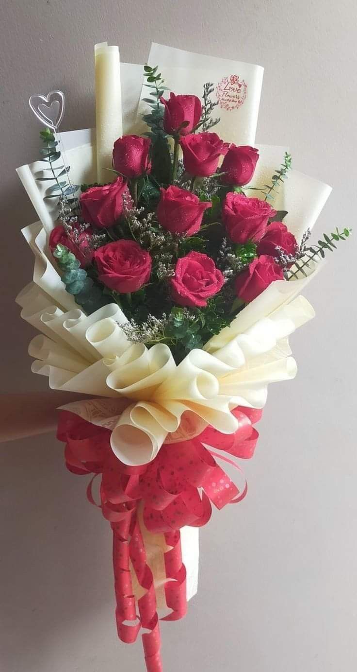 a bouquet of red roses is held by someone's hand with some writing on it