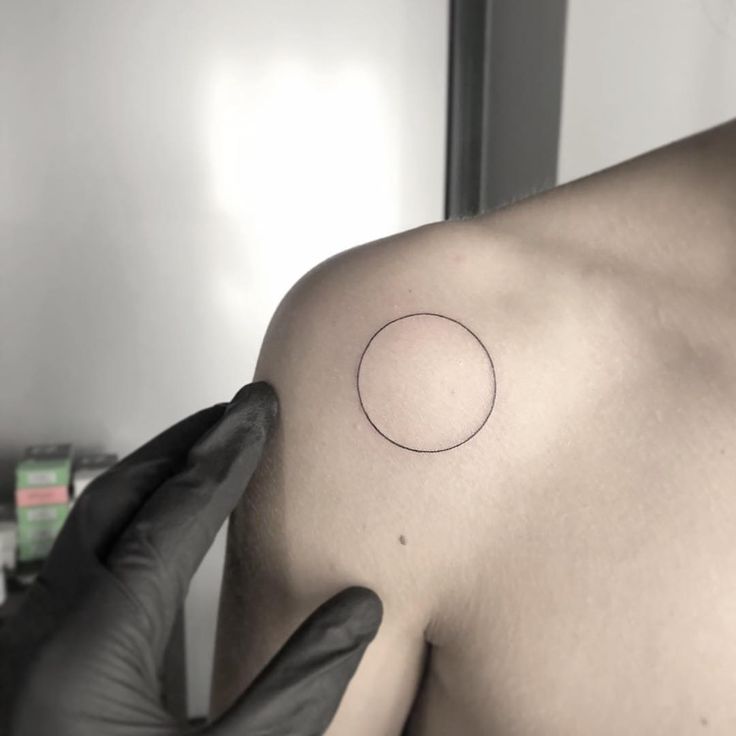 a man with a tattoo on his shoulder is looking at the camera while wearing gloves