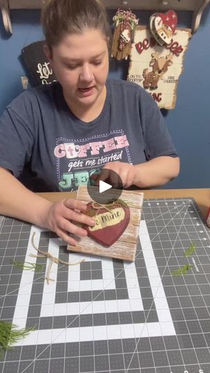 a woman sitting at a table making a heart shaped box