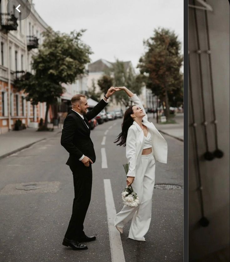 a man and woman standing in the middle of an empty street with their hands together