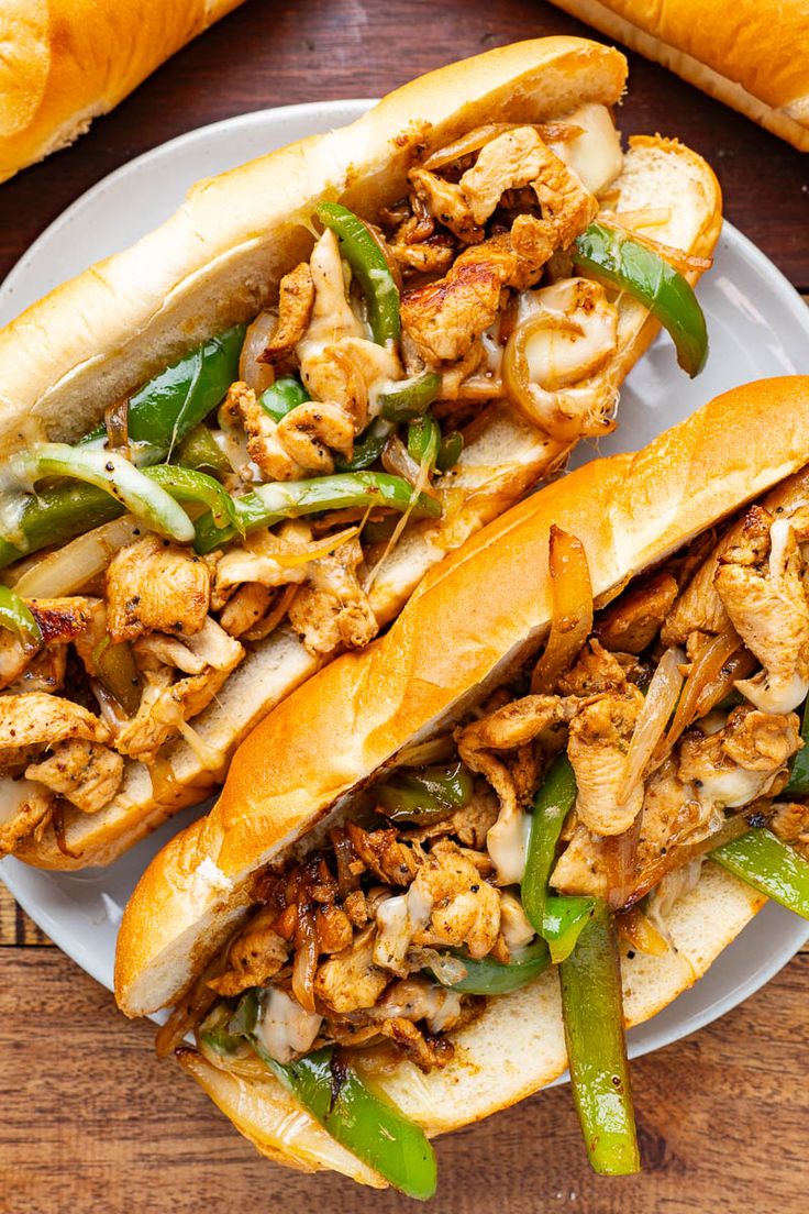 two sandwiches with meat, green beans and onions on a white plate next to bread