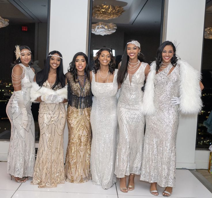 a group of women standing next to each other wearing dresses and feathers on their head