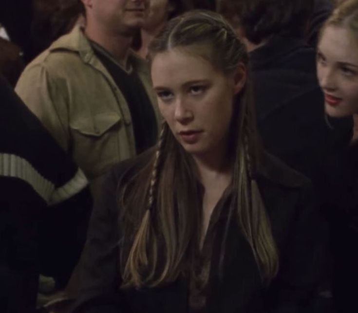 a group of people sitting next to each other in a room with one woman looking at the camera