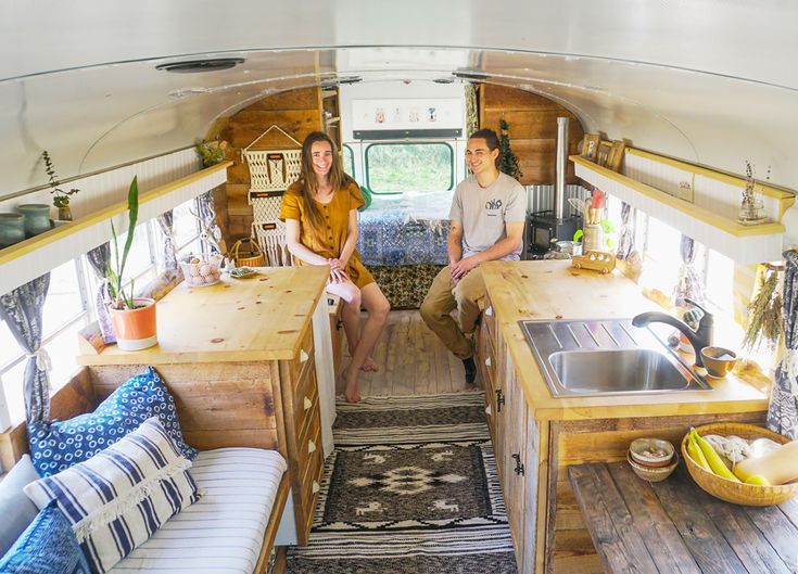 two women are sitting in the kitchen area of a camper with wooden cabinets and counter tops