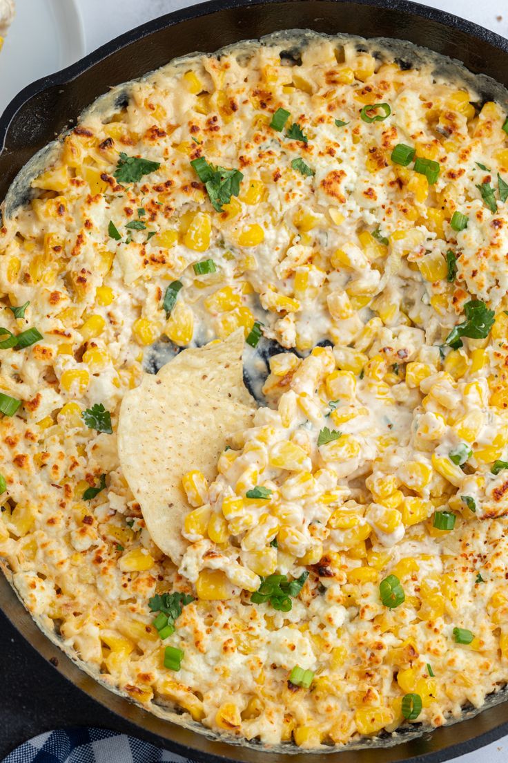 a skillet filled with corn and tortilla chips on top of a table