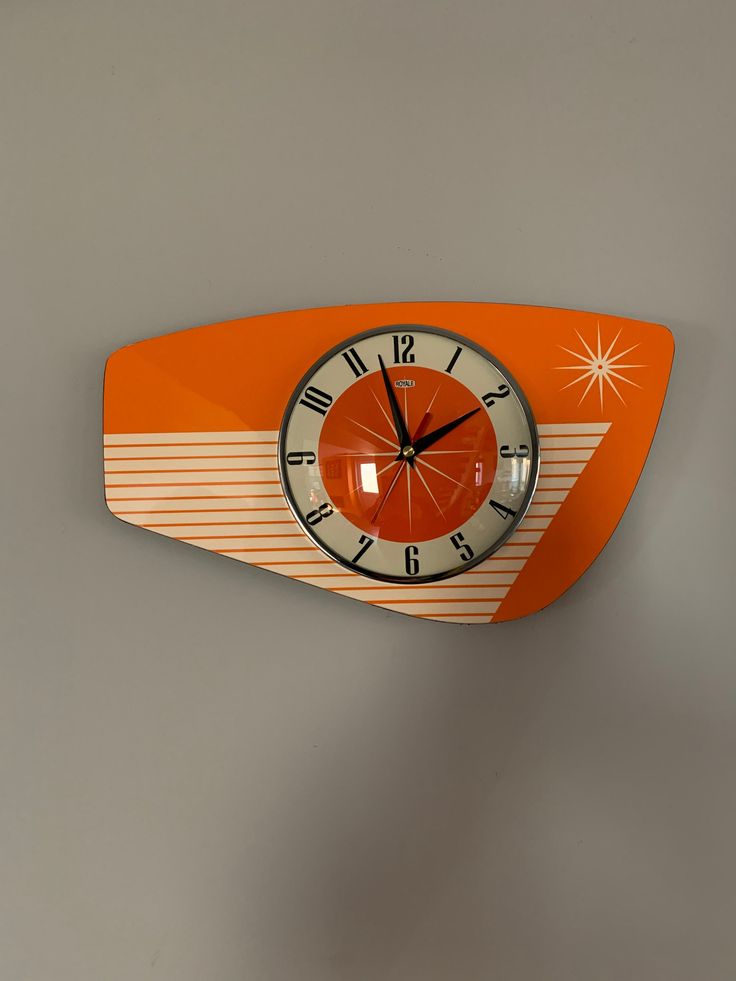 an orange and white clock mounted to the side of a wall