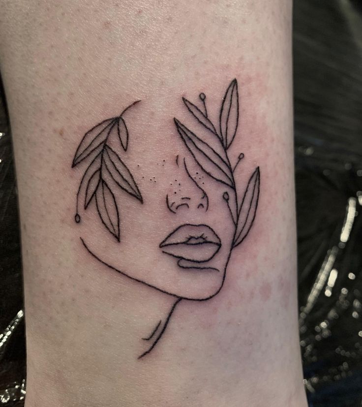 a woman's face with leaves in her hair on the side of her leg