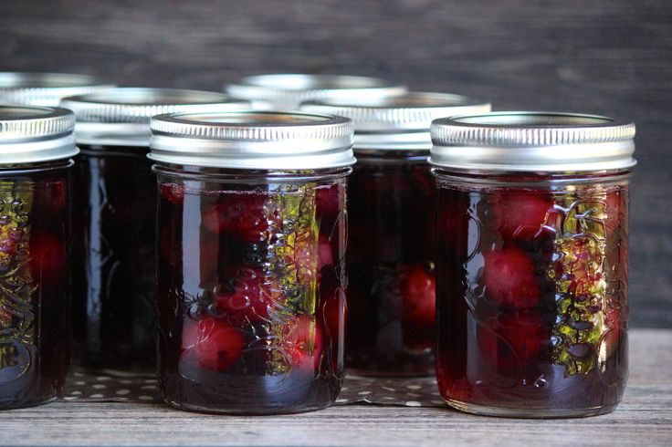 several jars filled with cherries sitting on top of a wooden table next to each other