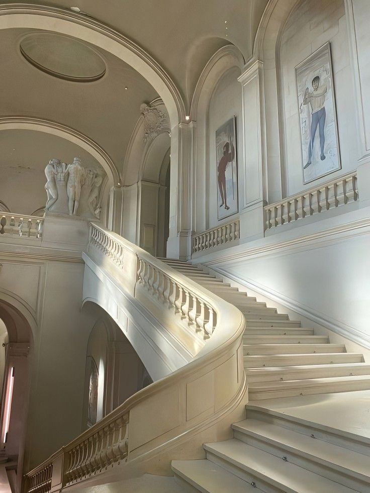 an ornate staircase with paintings on the walls and ceiling in a large white palace like building