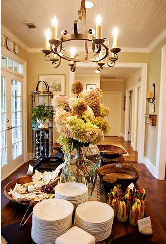 a dining room table filled with plates and bowls next to a vase full of flowers