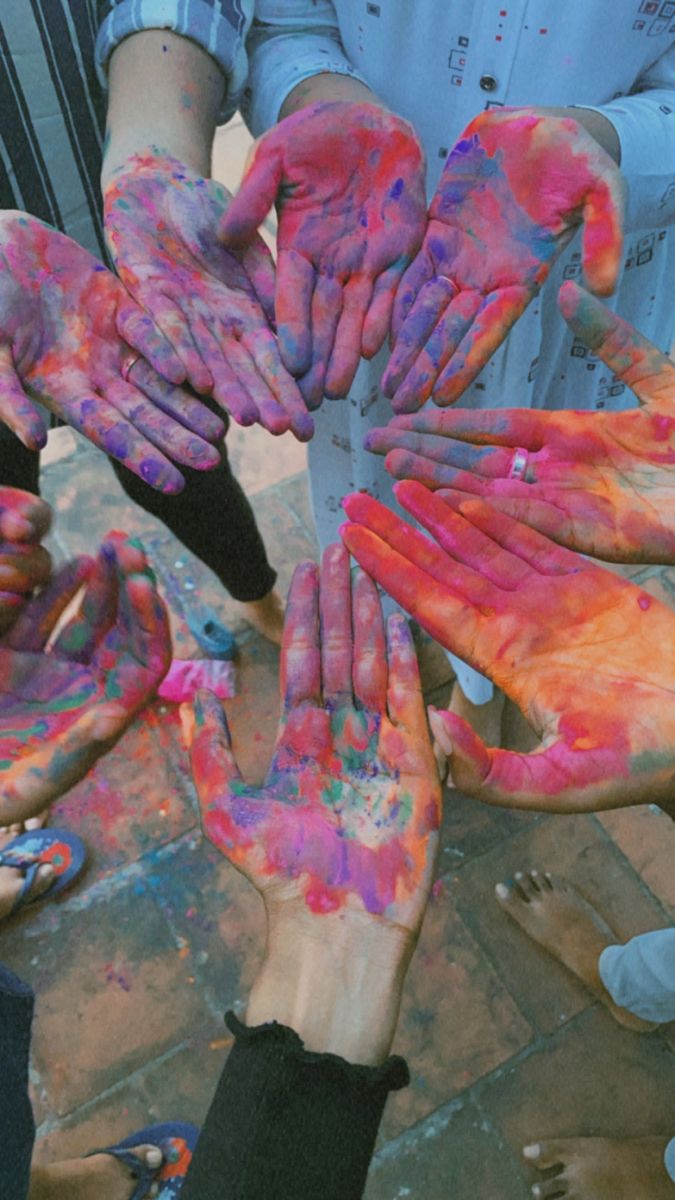 many people are holding their hands together with colored paint all over them