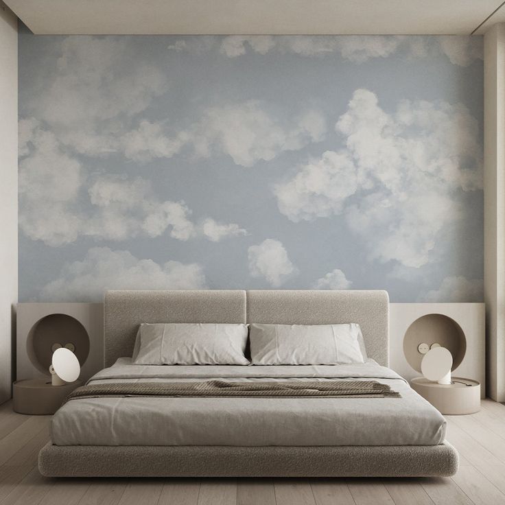 a large bed sitting in the middle of a bedroom next to a wall with clouds painted on it