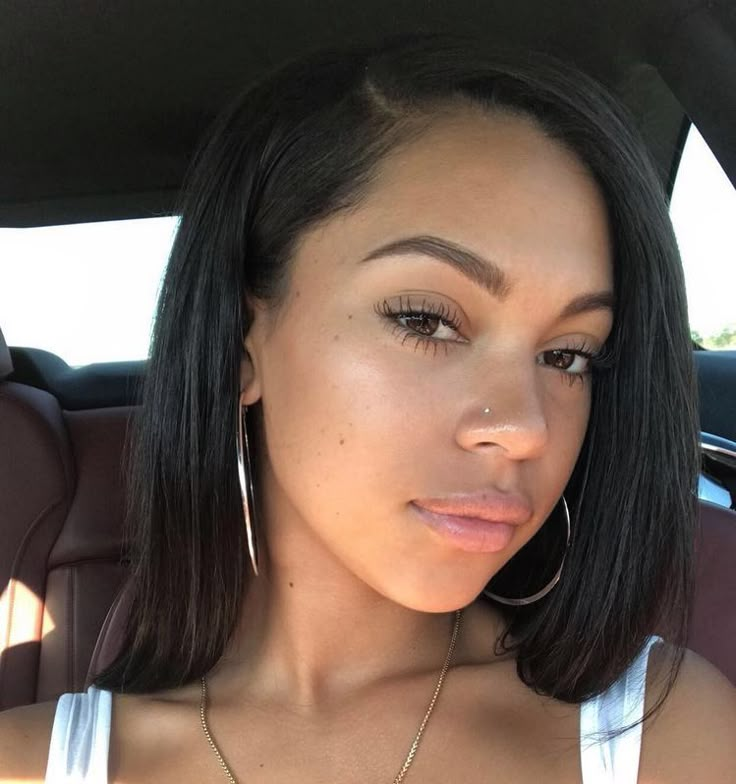 a woman sitting in the back seat of a car with large hoop earrings on her head