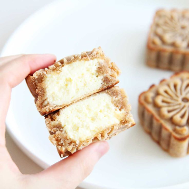 someone is holding some kind of dessert on a plate with other pastries in the background