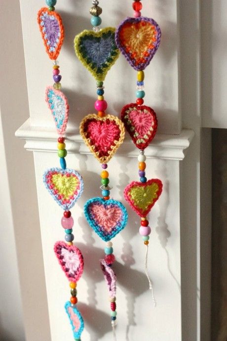 crocheted hearts hanging from the side of a white door with beads and chains