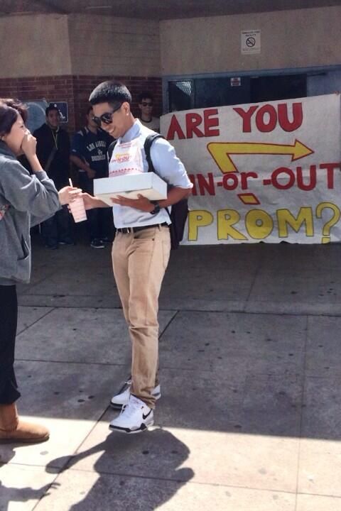 two people standing in front of a sign that says are you non - out prom?