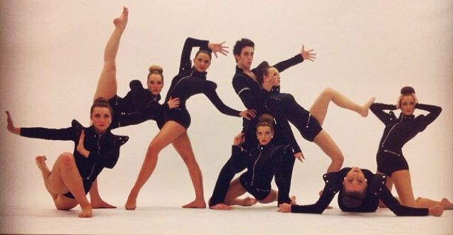 a group of dancers posing for a photo in black leotards and bodysuits