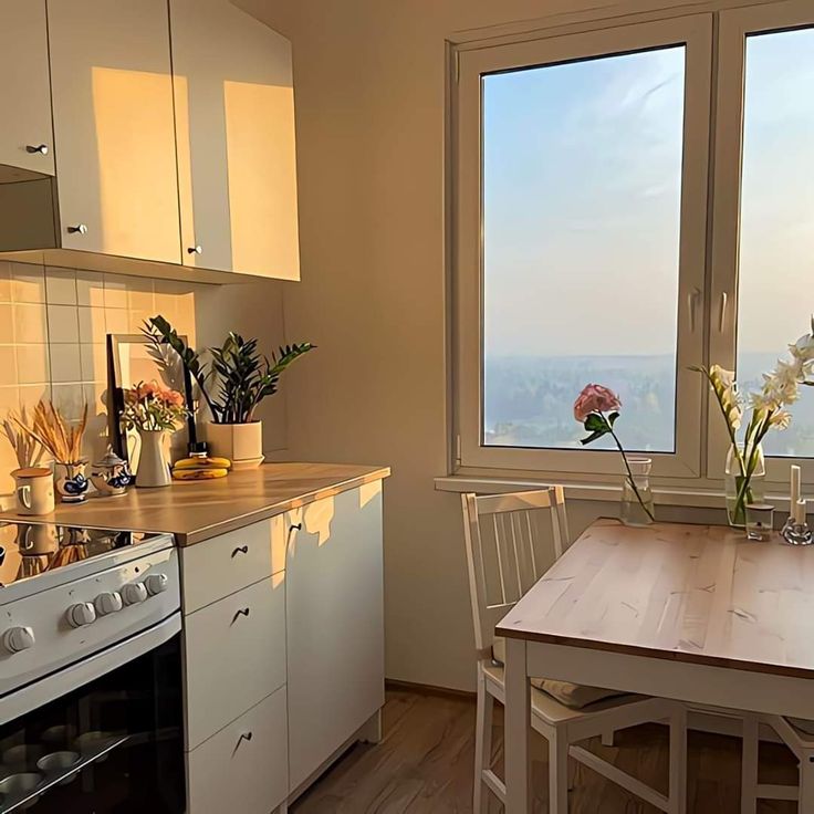 a kitchen with an oven, table and window overlooking the city below in daylight hours