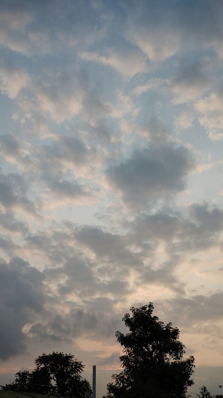 the sky is filled with clouds and there are trees in the foreground, as well as an obelisk