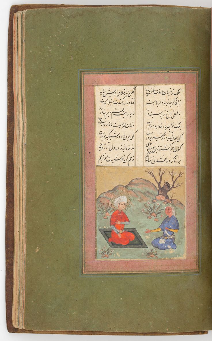 an old book with arabic writing on the cover and two men sitting in front of it