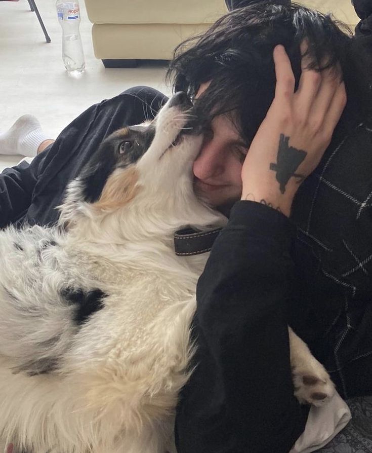 a person laying on the floor with a dog in their lap and one hand over his face