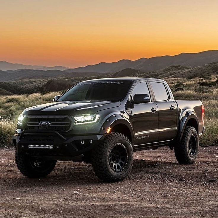 a black truck parked on top of a dirt field