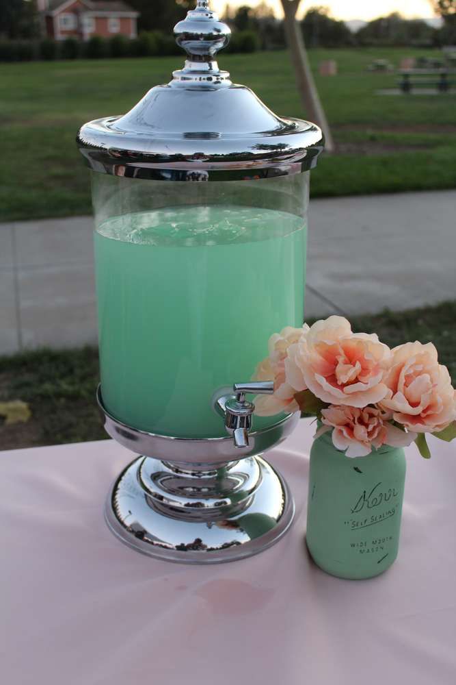 a vase with flowers sitting on top of a table next to a jar filled with liquid