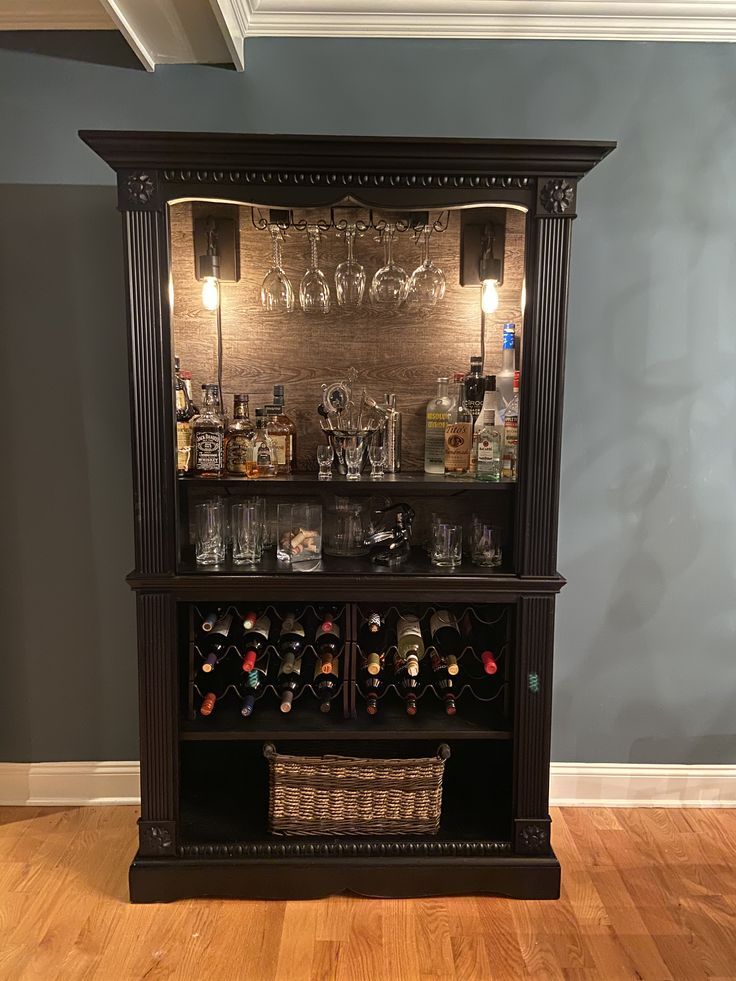 a wooden cabinet filled with lots of bottles and glasses on top of a hard wood floor