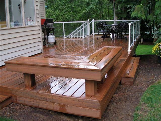 a wooden deck with steps leading up to the back door and table on the other side