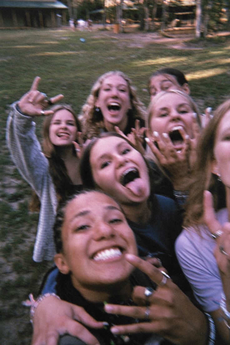 a group of young people standing next to each other on top of a grass covered field