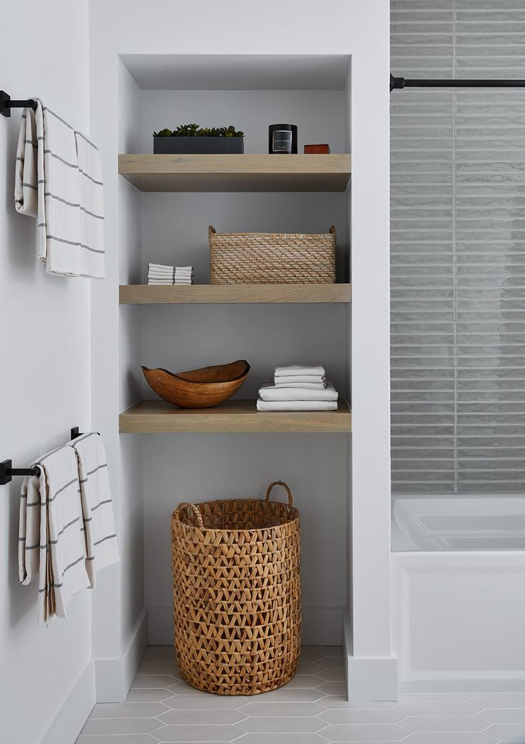 a bathroom with white walls and open shelving, baskets on the shelf next to the bathtub