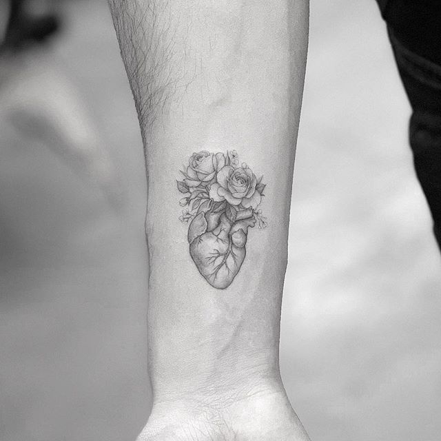 a black and white photo of a person's arm with a heart tattoo on it